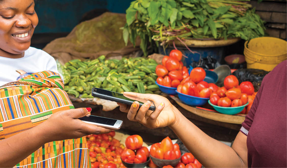 african woman in a market receiving payment via contactless transfer of funds from a customer using their mobile phones