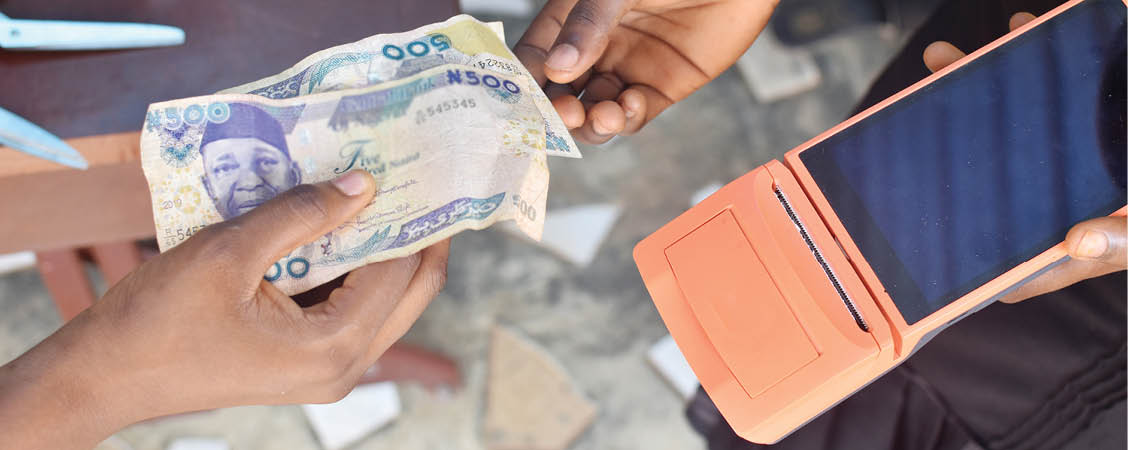 Tendering Nigerian naira note in a cash transaction with the help of point of sales POS terminal in a tailoring fashion designing shop